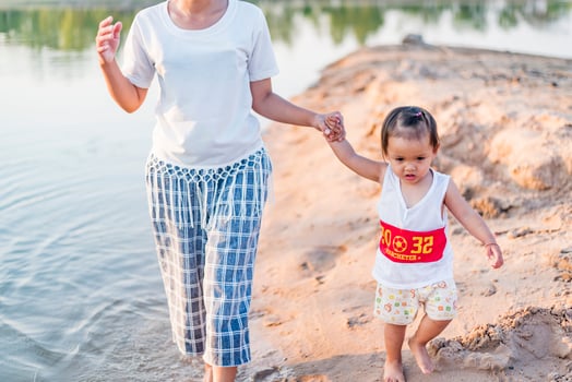 A young mother plays with her 2-5 year old daughter on the beach in summer. Outdoor resort on the lake Have a good rest on weekends, family days. photo