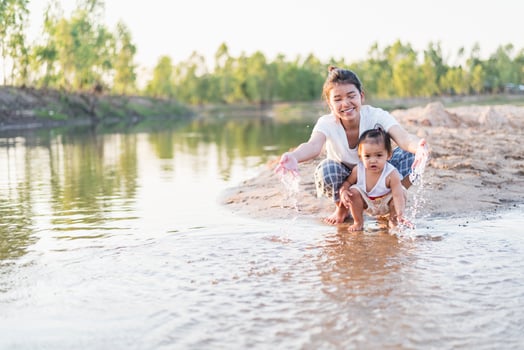 A young mother plays with her 2-5 year old daughter on the beach in summer. Outdoor resort on the lake Have a good rest on weekends, family days. photo
