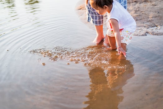 A young mother plays with her 2-5 year old daughter on the beach in summer. Outdoor resort on the lake Have a good rest on weekends, family days. photo