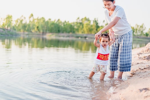 A young mother plays with her 2-5 year old daughter on the beach in summer. Outdoor resort on the lake Have a good rest on weekends, family days. photo