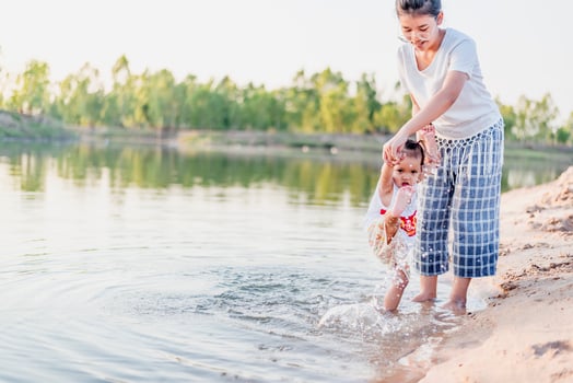 A young mother plays with her 2-5 year old daughter on the beach in summer. Outdoor resort on the lake Have a good rest on weekends, family days. photo