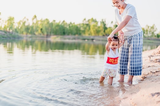 A young mother plays with her 2-5 year old daughter on the beach in summer. Outdoor resort on the lake Have a good rest on weekends, family days. photo