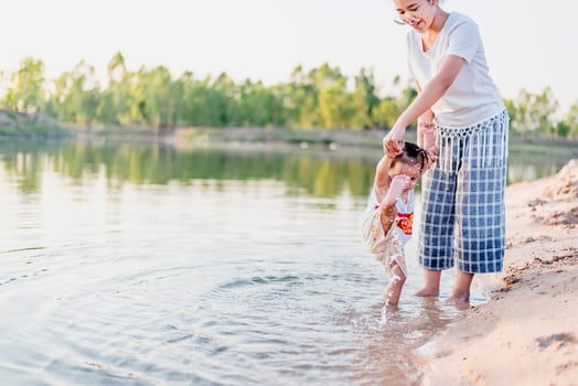 A young mother plays with her 2-5 year old daughter on the beach in summer. Outdoor resort on the lake Have a good rest on weekends, family days. photo