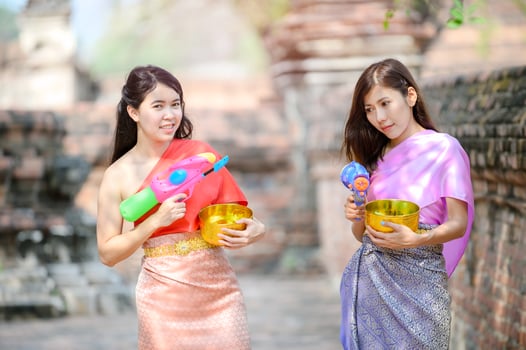 Beautiful Asian women hold plastic water guns at an ancient temple during Songkran, the most beautiful and fun water festival in Thailand photo