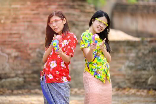 Beautiful Asian women hold plastic water guns at an ancient temple during Songkran, the most beautiful and fun water festival in Thailand photo