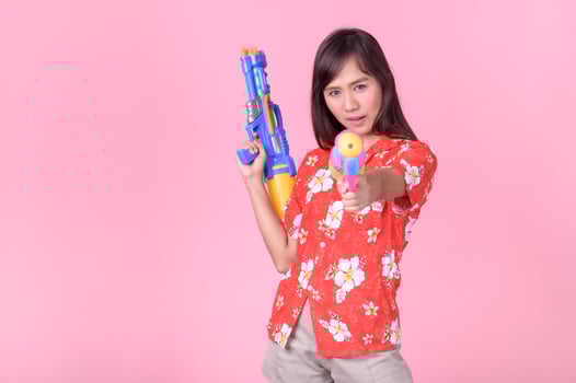 A beautiful Asian woman shows a gesture while holding a plastic water gun during the Songkran festival photo