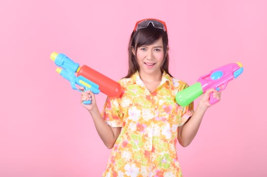 A beautiful Asian woman shows a gesture while holding a plastic water gun during the Songkran festival photo