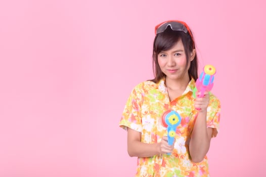 A beautiful Asian woman shows a gesture while holding a plastic water gun during the Songkran festival photo