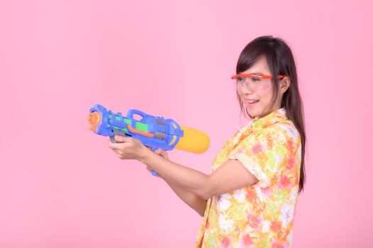 A beautiful Asian woman shows a gesture while holding a plastic water gun during the Songkran festival photo