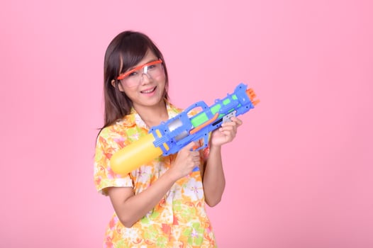 A beautiful Asian woman shows a gesture while holding a plastic water gun during the Songkran festival photo
