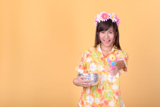 A beautiful Asian woman shows a gesture while holding a plastic water gun during the Songkran festival photo