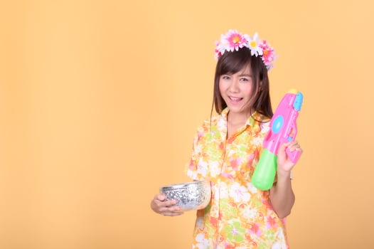 A beautiful Asian woman shows a gesture while holding a plastic water gun during the Songkran festival photo