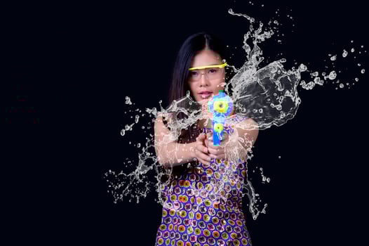A beautiful Asian woman shows a gesture while holding a plastic water gun during the Songkran festival photo