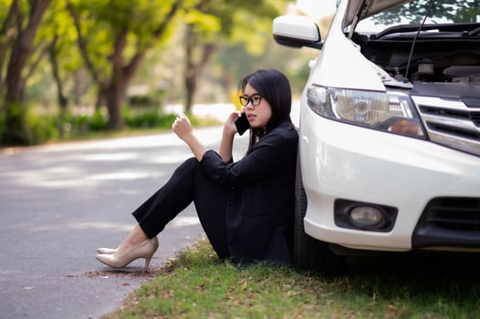 A young Asian woman is calling her service technician to fix a broken car on the side of the road photo