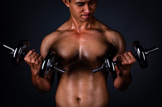 The strong Asian man lifted his dumbbell regularly to keep his muscles strong and beautiful photo