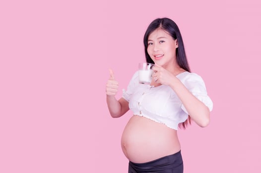 A beautiful pregnant woman standing and drinking fresh milk for good health for her future baby photo