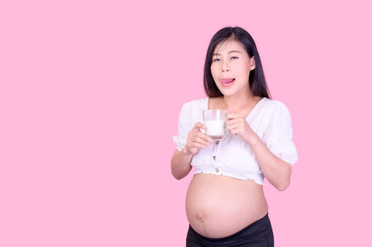 A beautiful pregnant woman standing and drinking fresh milk for good health for her future baby photo