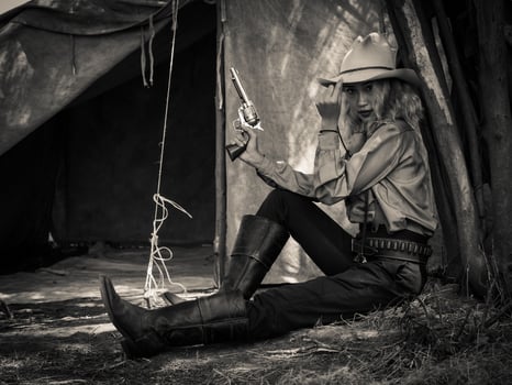 A young cowgirl sat with a gun to guard the safety of the camp in the western area photo