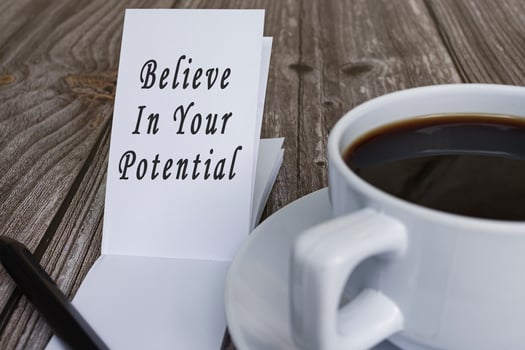 Motivational quotes on note pad on wooden desk - Believe in your potential. photo