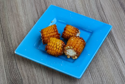 Grilled corn on the plate and wooden background photo