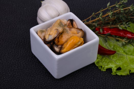 Pickled mussels in the bowl served pepper, garlic and salad photo