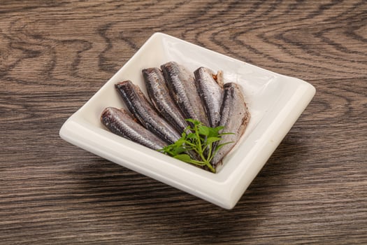 Anchovies in the bowl served basil leaves photo
