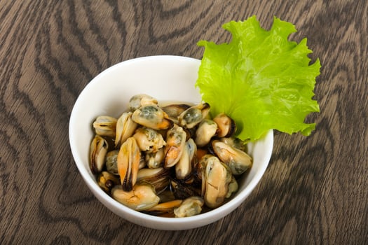 Pickled mussels in a bowl on wooden background photo