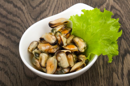 Pickled mussels in a bowl on wooden background photo