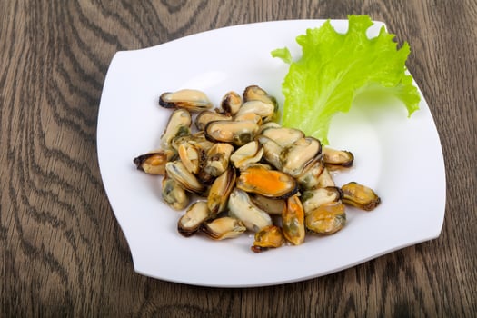 Pickled mussels on the plate and wooden background photo