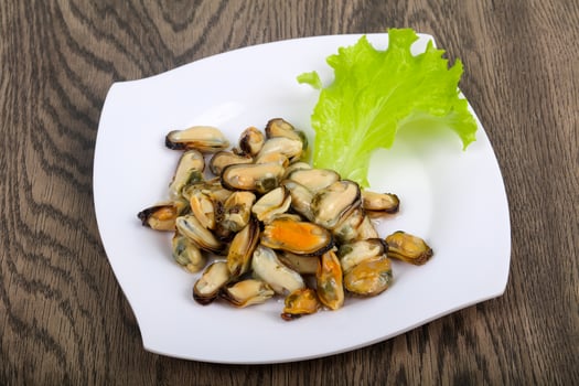 Pickled mussels on the plate and wooden background photo