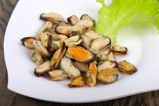 Pickled mussels on the plate and wooden background photo