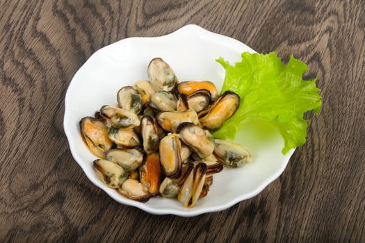 Pickled mussels on the plate and wooden background photo