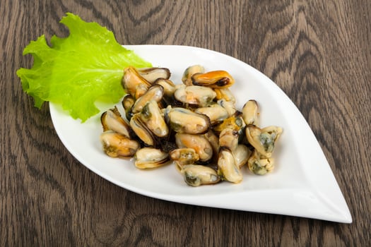 Pickled mussels on the plate and wooden background photo