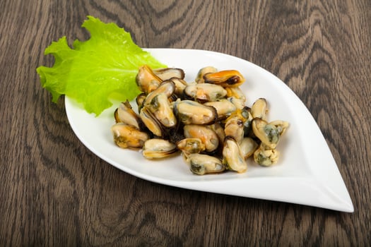 Pickled mussels on the plate and wooden background photo