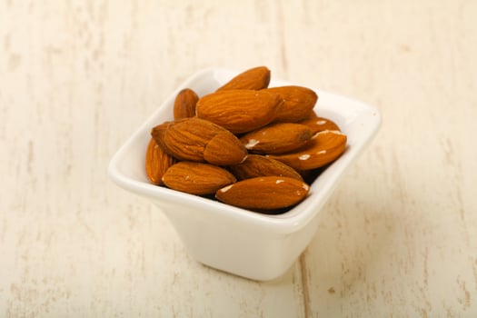 Almond nuts in a bowl on wooden background photo