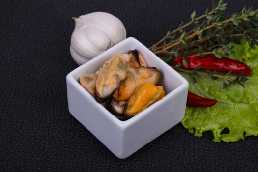 Pickled mussels in the bowl served pepper, garlic and salad photo
