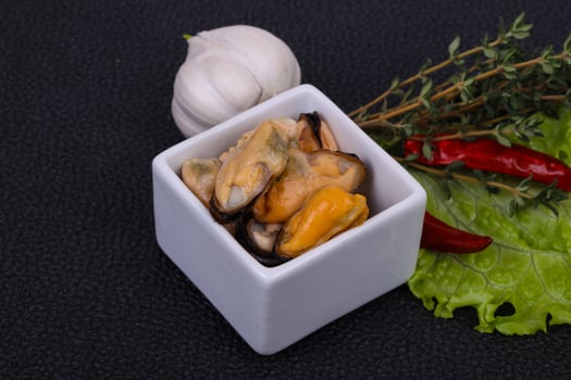 Pickled mussels in the bowl served pepper, garlic and salad photo