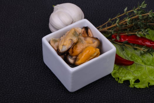 Pickled mussels in the bowl served pepper, garlic and salad photo