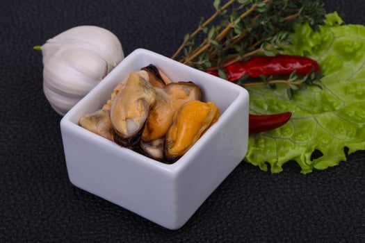 Pickled mussels in the bowl served pepper, garlic and salad photo
