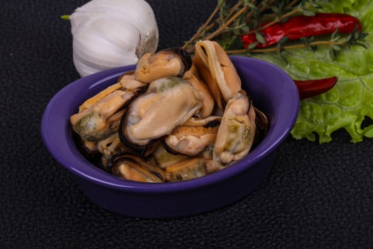 Pickled mussels in the bowl served pepper, garlic and salad photo