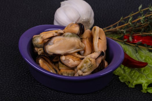 Pickled mussels in the bowl served pepper, garlic and salad photo