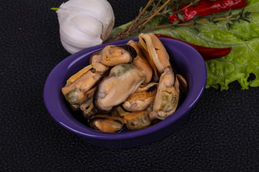 Pickled mussels in the bowl served pepper, garlic and salad photo