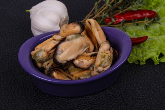 Pickled mussels in the bowl served pepper, garlic and salad photo