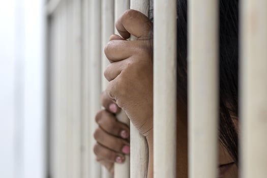 The hand of the accused woman caught the bars of the prison room. photo