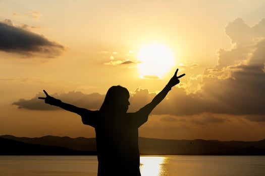 Silhouette of woman standing arms raised in the sunset. Strong female with open arms silhouette in sunrise against sun flare. Carefree person living a free life. Success freedom happy life concept. photo