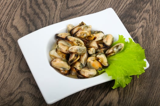 Pickled mussels in a bowl on wooden background photo