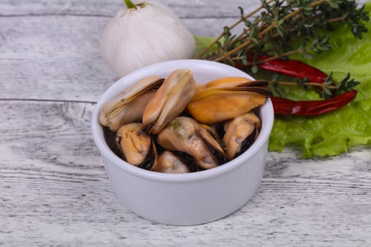 Pickled mussels in the bowl served pepper, garlic and salad photo