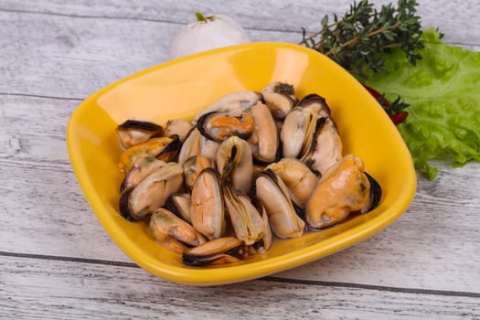Pickled mussels in the bowl served pepper, garlic and salad photo