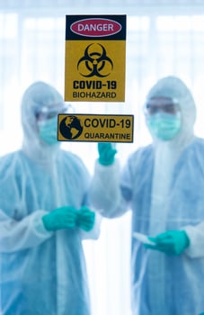 COVID-19, Corona Virus outbreak quarantine epidemic spread  social distancing concept. Blur Asian doctors wear PPE suit glove and face mask showing CORONA or COVID-19 vaccine behind danger sign photo