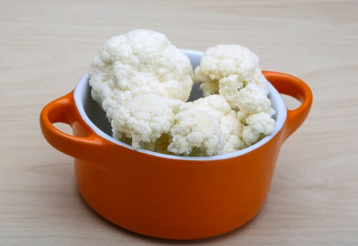 Cauliflower in a bowl on wooden background photo